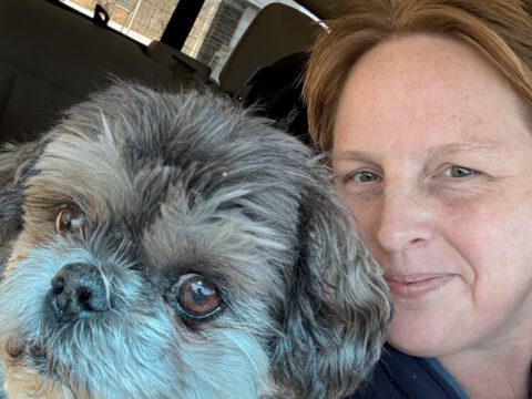 Founder Sandi Maki smiling alongside her Shih Tzu companion dog Milo inside a vehicle at Legendary Acres.
