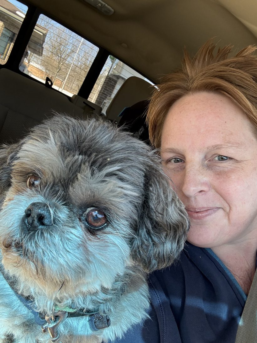 Founder Sandi Maki smiling alongside her Shih Tzu companion dog Milo inside a vehicle at Legendary Acres.